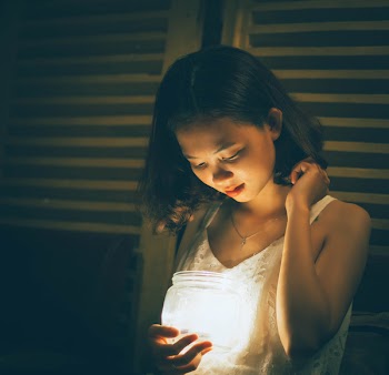 Woman Holding Jar With Light Beside Window