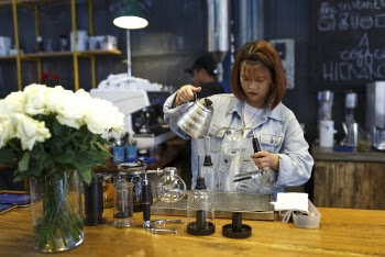 Woman Holding Kettle While Standing at the Table