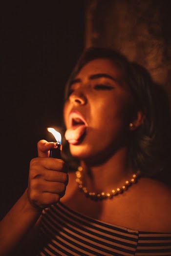 Woman Holding Lighted Disposable Lighter Showing Tongue