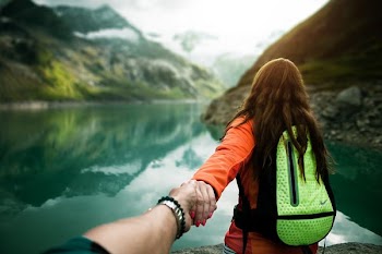 woman holding man's hand in front of water