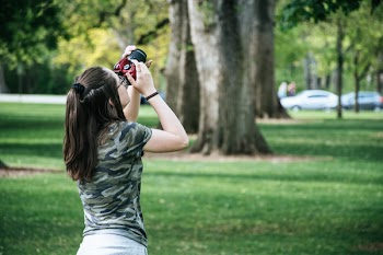 Woman Holding Maroon And Black Camera Facing Upwards