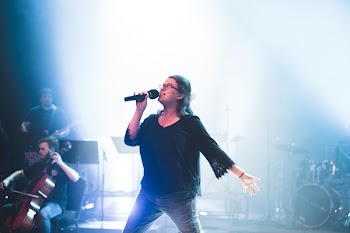 Woman Holding Microphone While Singing on Stage