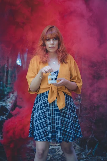 Woman Holding Mini Bird Cage in Front Red Smoke