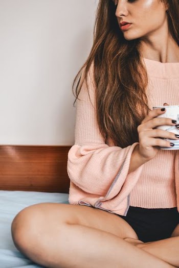 woman holding mug sitting on bed