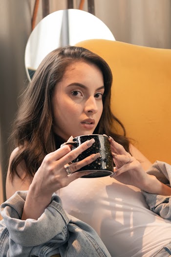 Woman Holding Mug Sitting On Yellow Sofa