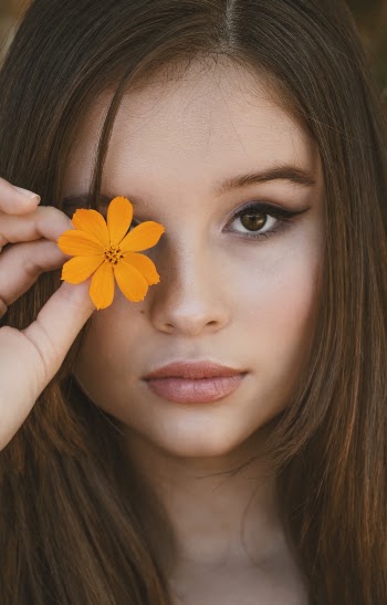 Woman Holding Orange Flower Over Right Eye