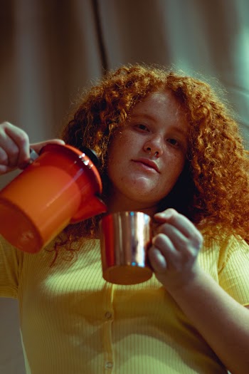 Woman Holding Orange Pitcher and Glass Mug