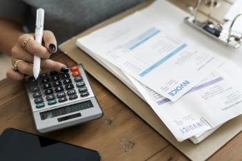 Woman Holding Pen While Using Calculator