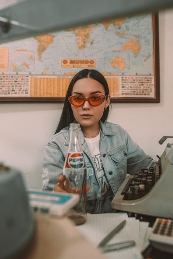 woman holding Pepsi bottle near typewriter