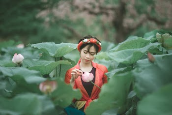 Woman Holding Pink Flower In The Middle Of Lily Plants