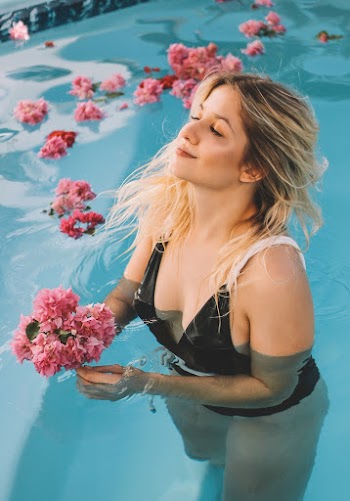 Woman Holding Pink Flowers In Swimming Pool