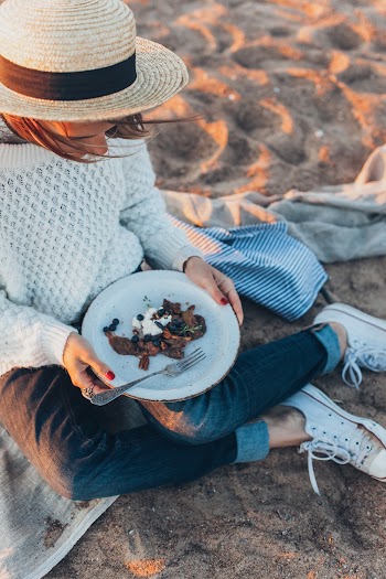 Woman Holding Plate While Sitting on Sand