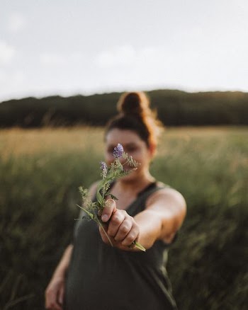 woman holding purple flower near grasses