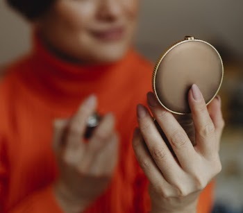 Woman Holding Round Brown Pressed Powder Case