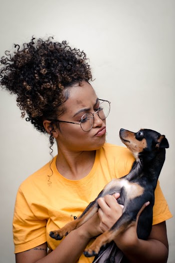Woman Holding Short-coated Black and Brown Puppy