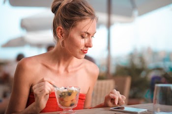 Woman Holding Silverware While Looking at Phone