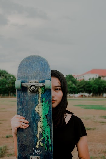 Woman Holding Skateboard Covering Her eyes