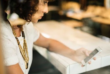 woman holding smartphone and sitting near the table