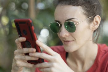 Woman Holding Smartphone and Wearing Sunglasses