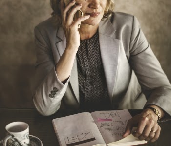 Woman Holding Smartphone While Sitting on Chair