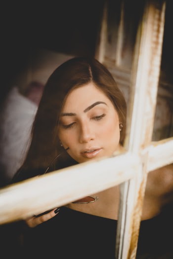 Woman Holding Sunglasses Near Window
