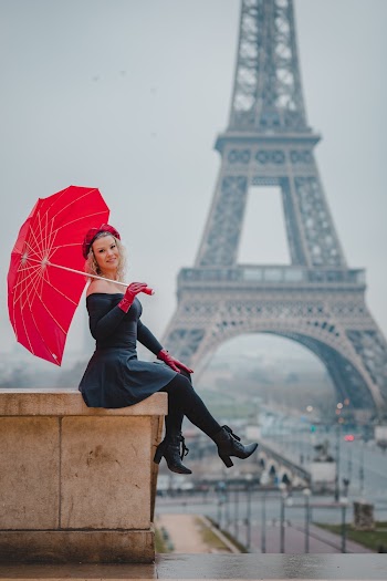 Woman Holding Umbrella Sitting In Front Of Eiffel Tower