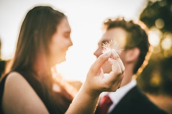 Woman Holding White Dandelion Seed Head While Facing Man
