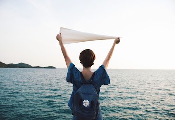 woman holding white pennant in front of body of water
