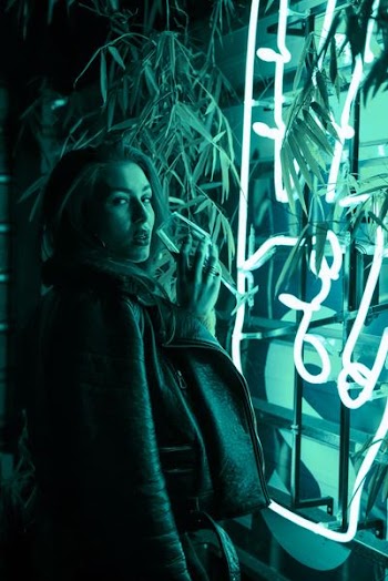 woman holding wine glass in front of green light signage