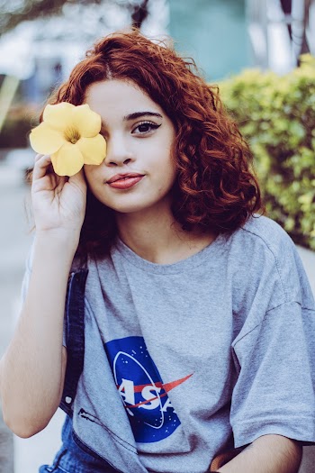 Woman Holding Yellow Flower on Right Eye