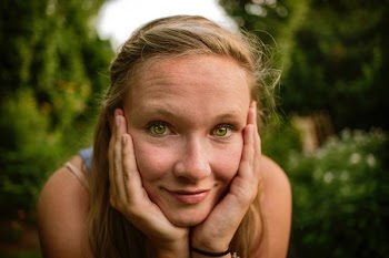 woman holds face near grasses