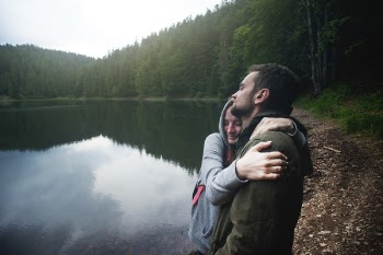 Woman Hugging Man Standing Beside Body of Water
