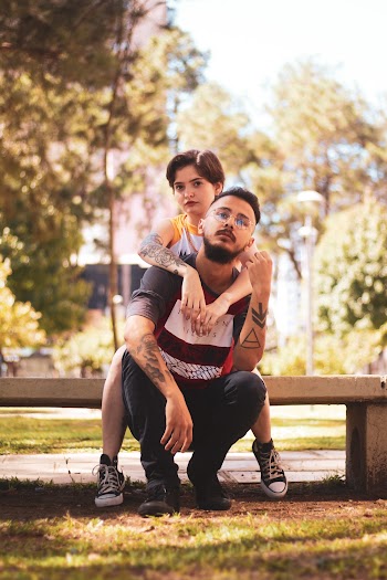 Woman Hugging Man Wearing Black Shirt While Sitting