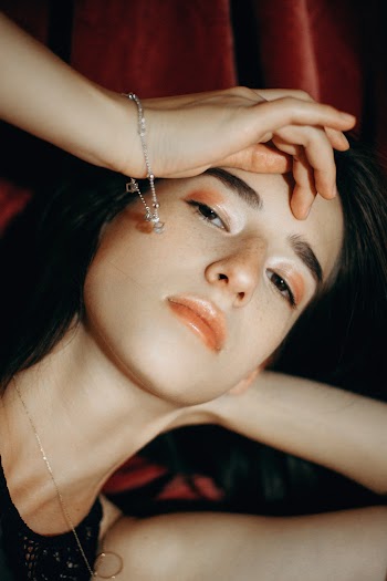 Woman In A Black Top And Jewelry Touching Her Forehead