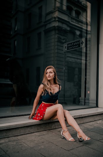 Woman in a black top and red skirt floral  sitting 