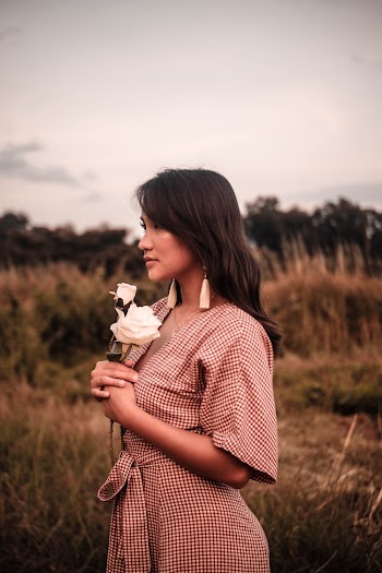 Woman In A Grassfield Holding White Flowers