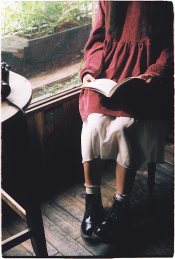 Woman in a Vintage Outfit Sitting and Reading a Book