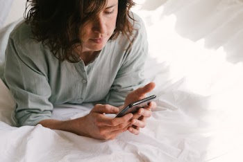 Woman In Bed Looking At Her Phone