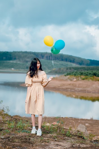 Woman in Beige Off-shoulder Dress Holding Balloons