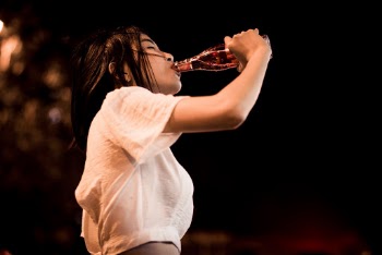 Woman in Beige Top Drinking from Bottle