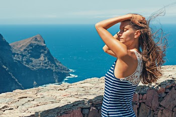 Woman in Black and Blue Striped Top Standing in Front of Wall