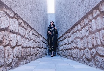 Woman in Black and Gold Traditional Dress Between Gray Concrete Walls