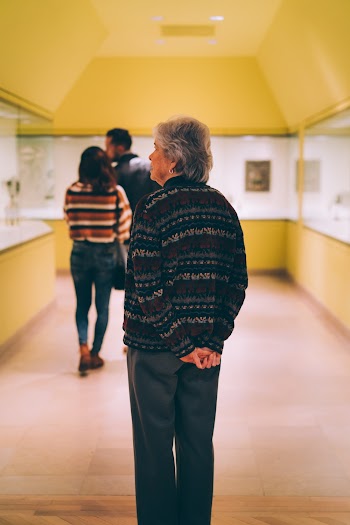 Woman in Black and Green Striped Knit Sweater Folding Her Hands Behind Her Back