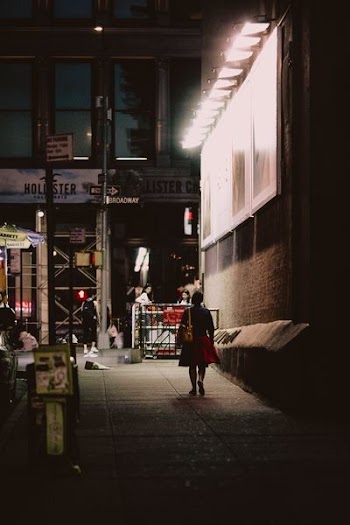 woman in black and red dress walking beside brown building