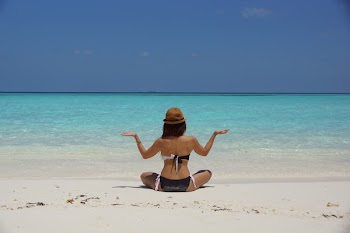 Woman in Black and White Bikini Sitting on White Stand Facing Beach during Daytime