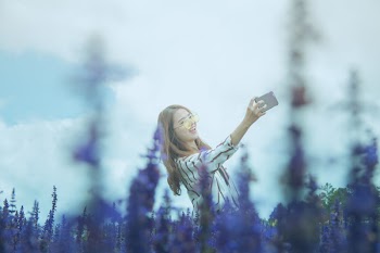 Woman in Black and White Dress Shirt Taking Photo on Lavender Flower Field at Daytime