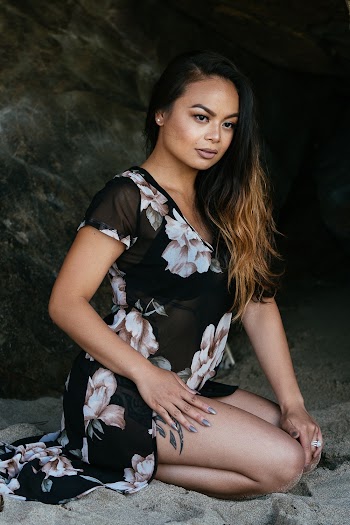 Woman in Black and White Floral Cap-sleeved Dress Sitting Down on Sand