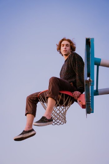 Woman in Black and White Long Sleeve Shirt and Brown Pants Sitting on Basketball Hoop · Free Stock Photo