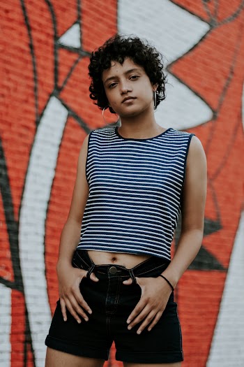 Woman in Black and White Striped Tank Top and Black Sunglasses Standing Near Wall
