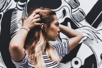 woman in black and white striped top standing near wall with graffiti